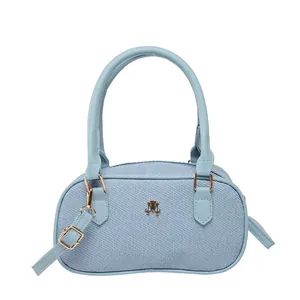 Minimalist light blue denim crossbody bag with dual handles and gold metal logo