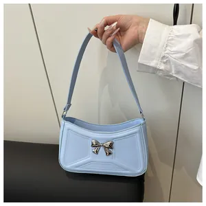 Détail du sac bandoulière bleu clair avec nœud en métal argenté et coutures géométriques