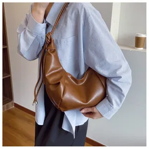 Close-up of brown PU leather hobo bag with pleated details and knotted shoulder strap