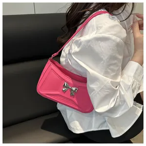Détail du sac sous le bras rose tendance avec nœud en métal argenté et texture matelassée