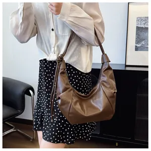 Detail of ruched brown PU leather shoulder bag with knotted strap on a female model
