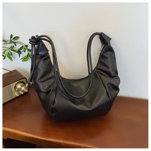 Detail of black pleated PU leather crescent bag with knot strap and silver zipper