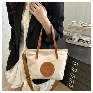 Detail of white nylon tote bag with brown leather patch and adjustable crossbody strap