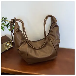 Detailed view of dark brown PU leather hobo bag with pleated texture and knotted rope strap