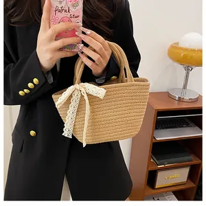 Détail d'un sac à main en paille tressé avec des nœuds décoratifs en dentelle blanche