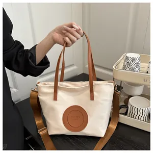 Close-up of cream canvas tote bag with brown leather handles and a wide shoulder strap