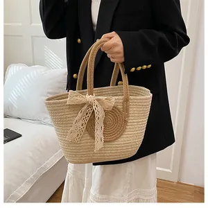 Detail der gewebten Stroh-Tasche mit braunen Akzenten und einer weißen Spitzen-Schleife