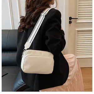 Detail of white lychee textured crossbody bag with black and white striped wide strap
