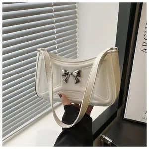 Détail du sac bandoulière blanc en similicuir avec nœud argenté et surpiqûres géométriques