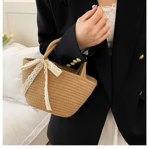 Détail du sac cabas en paille tissée avec nœud élégant en dentelle blanche et poignées