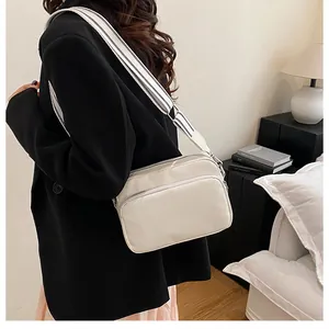 On-body view of a white crossbody bag with stylish black and white striped wide strap