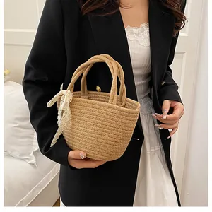 Détail d'un sac cabas en paille avec nœud en dentelle blanche et anses rondes solides