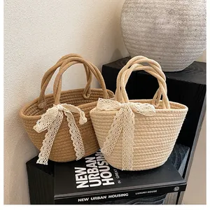Detailed close-up of handmade woven cotton straw bags with white lace bow decorations