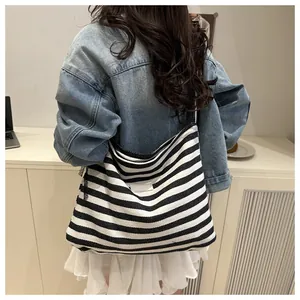 Detailed view of striped canvas tote bag worn by model in a natural casual setting