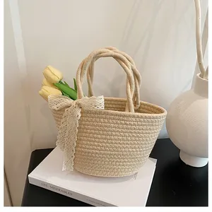 Detail of handmade straw woven bag featuring elegant white lace bow and round top handles