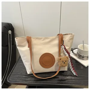 Detail of canvas tote bag with brown leather straps and fashion bags round emblem