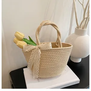 Detail of handmade straw woven bag with white lace bow and round handles