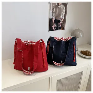 Detail of denim crossbody bag with red checkered drawstring and adjustable strap
