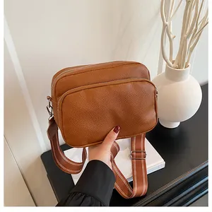 Detail of brown litchi pattern leather bag featuring double zippers and wide strap