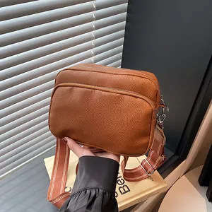Brown litchi grain crossbody bag with wide shoulder strap and double zippers design