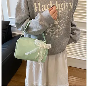 Detail einer minzgrünen Handtasche mit weißer Spitzenschleife und Perlenverzierungen