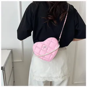 Detail of pink heart-shaped crossbody bag with quilted pattern and pearl chain accent