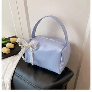 Detailansicht hellblaue Satinhandtasche mit weißer Spitze und Perlenanhänger im Schleifendesign
