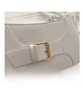 Gros plan d'un sac cabas en cuir blanc avec une boucle carrée en métal doré élégante