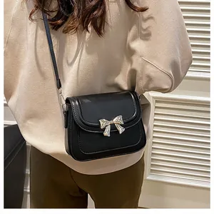 Dettaglio mini borsa a tracolla nera con fiocco in metallo argento e finitura opaca