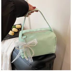 Detail der mintgrünen Handtasche mit Perlenspitzen-Bogenanhänger und glattem Kunstleder