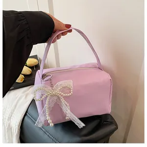 Detail der lila Nylon-Handtasche mit weißem Reißverschluss und Perlen-Schleifen-Anhänger