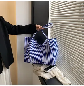Detail view of a large blue and white striped tote bag with a front pocket for daily use