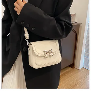 Dettaglio borsa a tracolla bianco avorio con fibbia a fiocco argento su modella in blazer