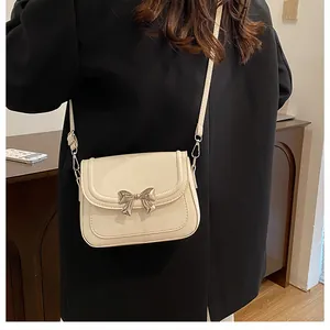 Dettaglio di una borsa beige con fibbia in metallo e cuciture sottili in ecopelle