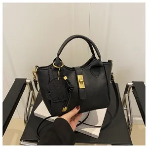 Detail van zwarte handtas van generfd leer met gouden slot en olifant hanger