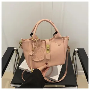 Detail van roze handtas met lychee-textuur, metalen draaisluiting en schattige beer