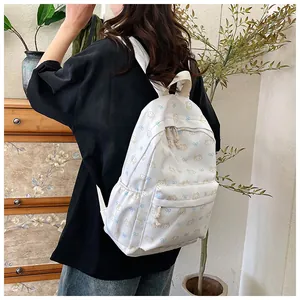 Dettaglio di un grande zaino scolastico bianco con motivo a gatto indossato da modella