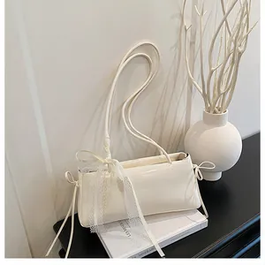 Detail of cream white underarm bag with lace bow and leather texture on a book