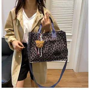 Detailed view of leopard print canvas tote with plush bear charm and crossbody strap