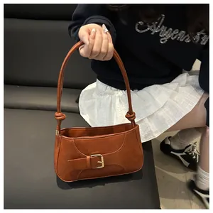 Détail du sac à bandoulière en cuir caramel avec boucle dorée et nœud élégant