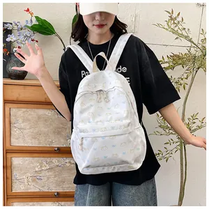 Dettaglio laterale di uno zaino in nylon bianco con motivi di gatti gialli e fiocchi blu