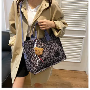 Detailed shot of leopard print canvas tote bag with blue straps and plush bear charm
