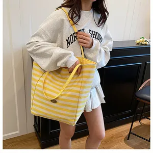 Détail du sac cabas en maille rayée jaune et blanc montrant la texture et la bandoulière