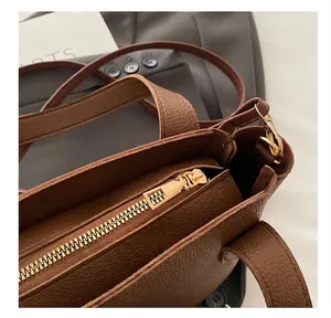 Detailed close-up of brown litchi grain leather bucket bag with smooth gold zipper