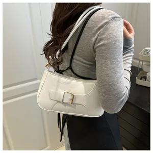 Détail du sac à bandoulière en cuir blanc avec boucle dorée porté par un mannequin femme