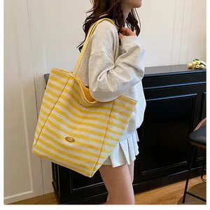 Détail du sac cabas en tricot rayé jaune et blanc avec texture toile et logo ovale