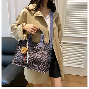 Leopard print canvas tote bag with purple straps and a brown plush bear charm detail