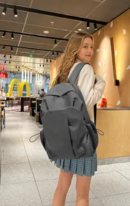 Détail du sac à dos en toile grise montrant la poche latérale avec cordon de serrage