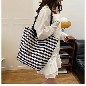 Détail du grand sac cabas en maille rayée avec étiquette cuir et anses confortables