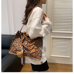 Macro detail of leopard print canvas tote bag with plush bear pendant and striped silk scarf